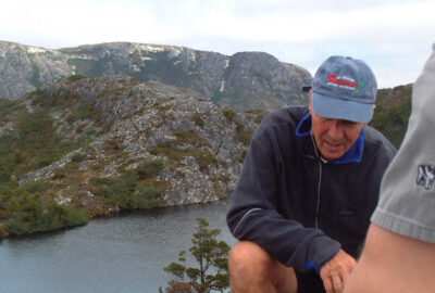 Alpine lake with mountain, and guide wearing baseball cap in foreground